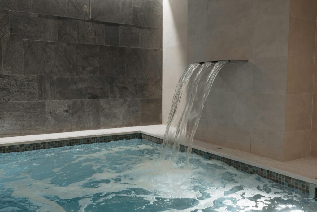 Luxury indoor pool with cascading waterfall and marble walls offering a serene spa experience.